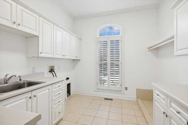 kitchen with white cabinets, light tile patterned floors, crown molding, and sink