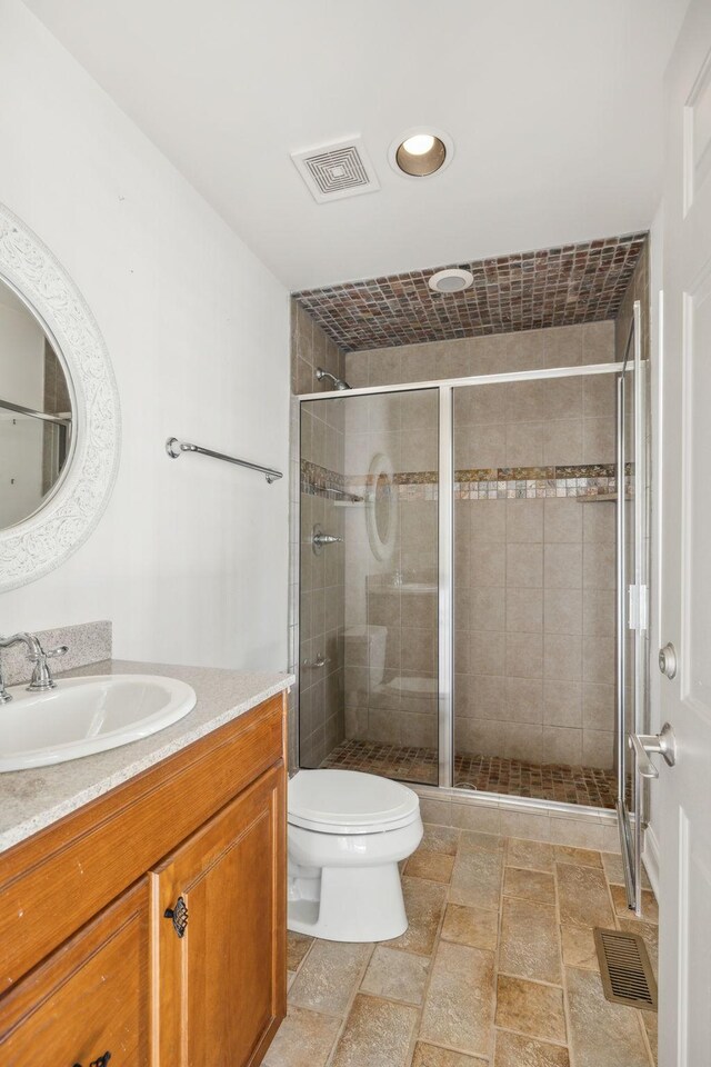 bathroom with vanity, toilet, and a shower with door