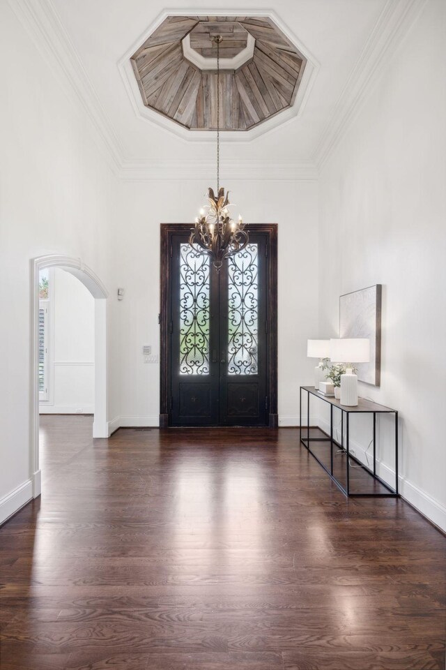 entryway featuring dark wood-type flooring, a wealth of natural light, a chandelier, and ornamental molding