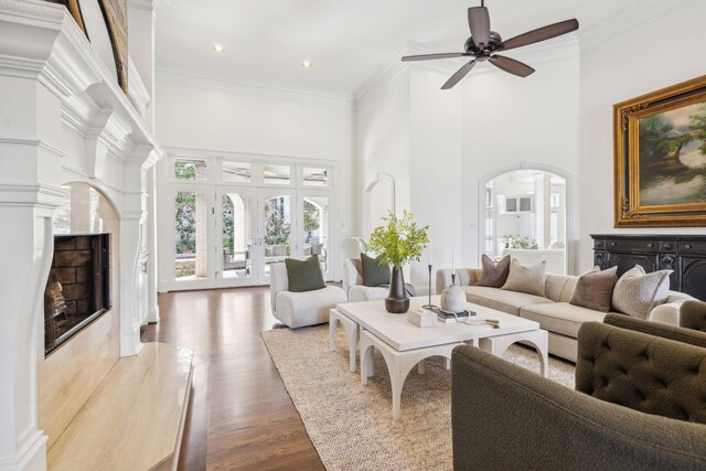 living room with a high end fireplace, french doors, crown molding, dark wood-type flooring, and a towering ceiling