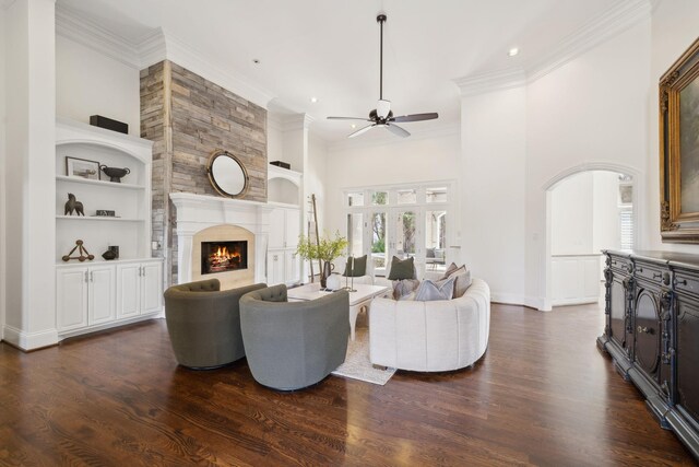 living room featuring a fireplace, crown molding, dark hardwood / wood-style flooring, built in features, and ceiling fan