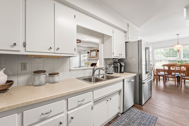 kitchen with white cabinets, dishwasher, light hardwood / wood-style floors, sink, and decorative backsplash