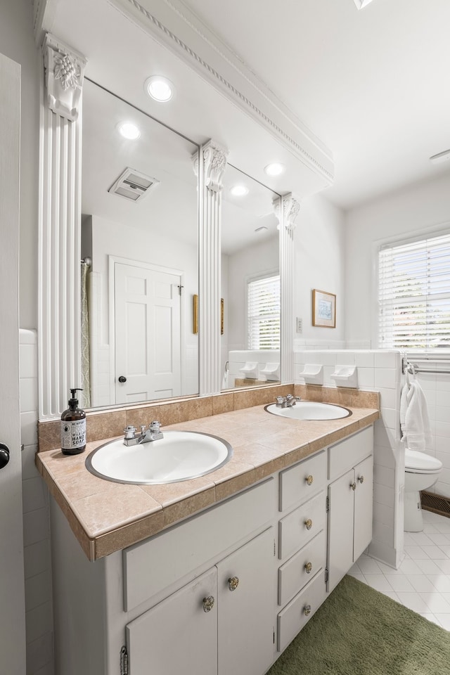 bathroom with tile patterned floors, tile walls, toilet, and vanity