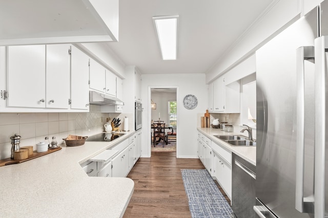 kitchen with wood-type flooring, appliances with stainless steel finishes, sink, decorative backsplash, and white cabinetry