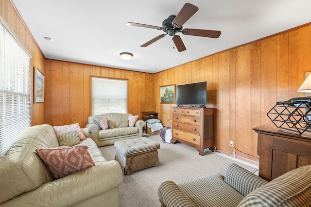 living room with light colored carpet, plenty of natural light, ceiling fan, and wooden walls