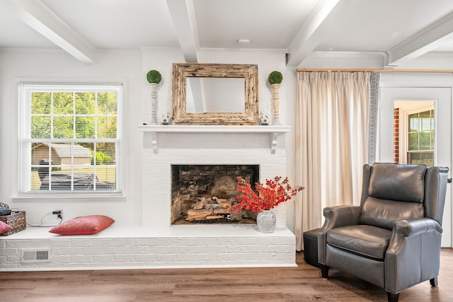 living area with ornamental molding, beamed ceiling, hardwood / wood-style flooring, and a fireplace