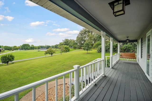 wooden terrace with a lawn and covered porch