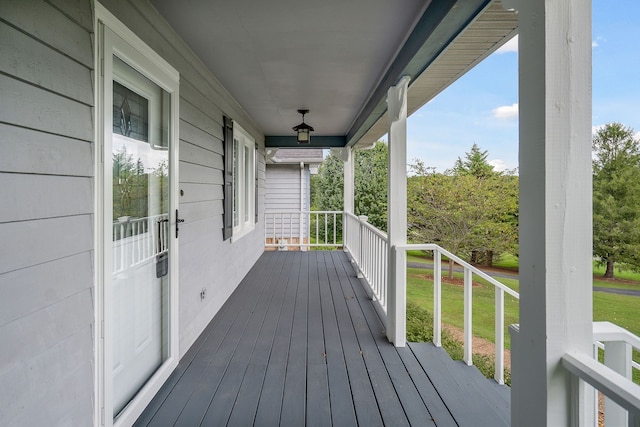 wooden terrace featuring a lawn and a porch