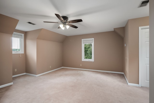 additional living space featuring ceiling fan, light colored carpet, and a healthy amount of sunlight