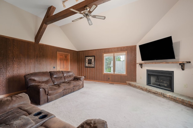 living room featuring ceiling fan, wood walls, beam ceiling, and a fireplace