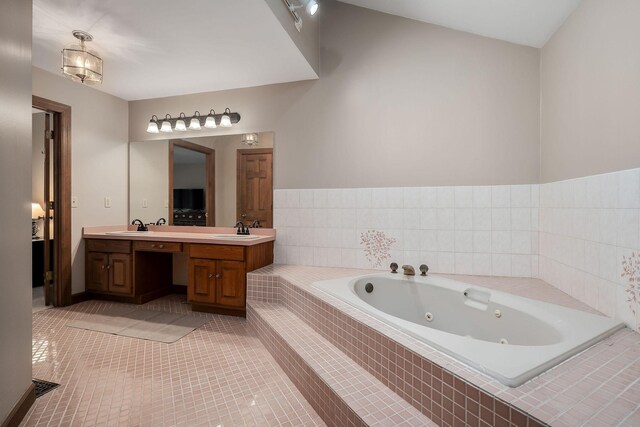 bathroom featuring tile patterned flooring, vanity, and a relaxing tiled tub