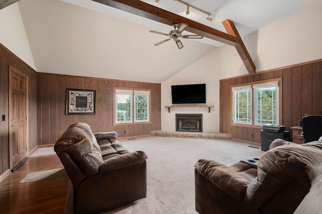 living room featuring ceiling fan, a wealth of natural light, wooden walls, and a brick fireplace