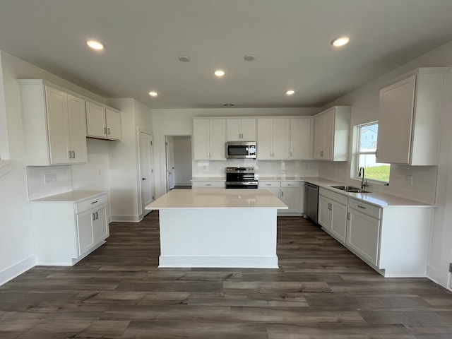 kitchen with appliances with stainless steel finishes, a sink, a center island, decorative backsplash, and white cabinetry