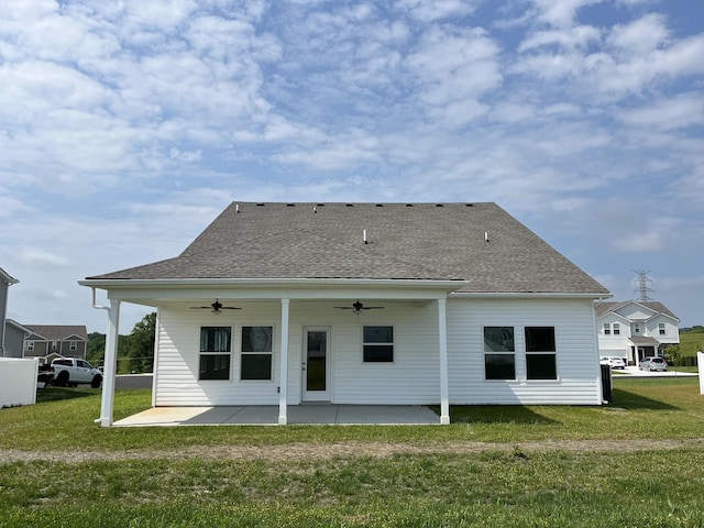rear view of property featuring ceiling fan, a patio, a yard, and a shingled roof