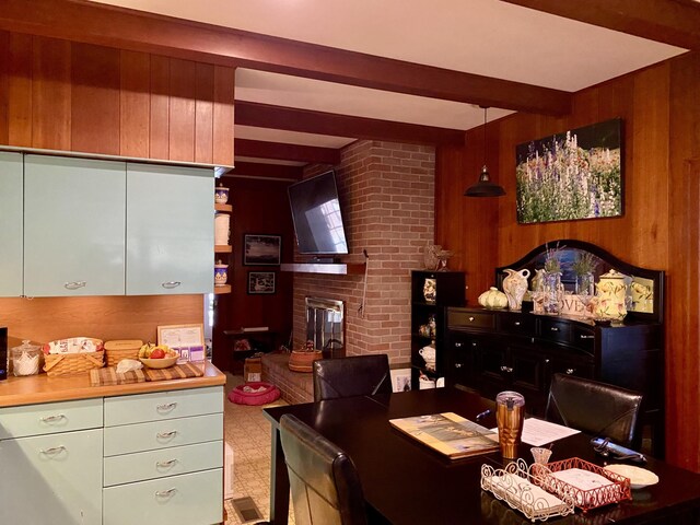 dining space featuring a brick fireplace, beamed ceiling, and wooden walls