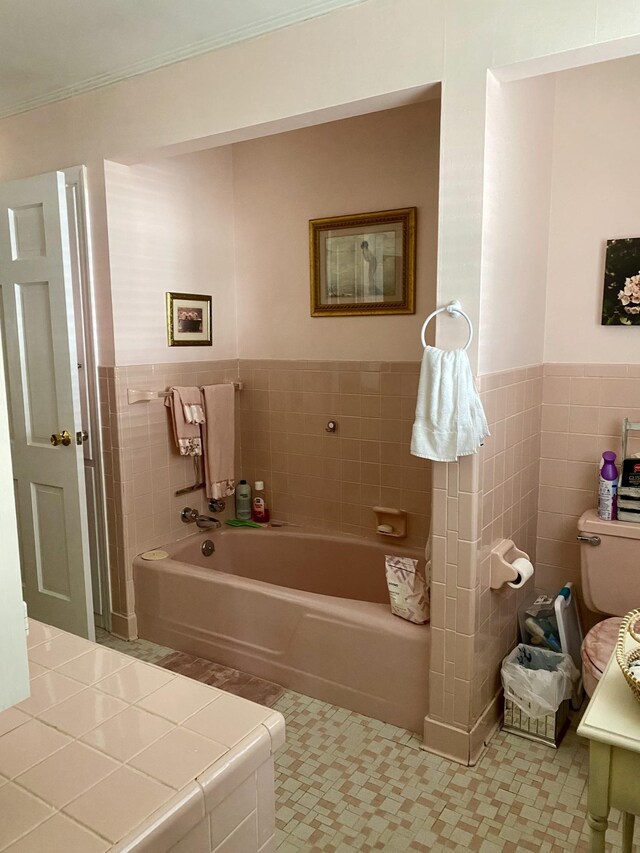 bathroom with ornamental molding, tile walls, and a tub