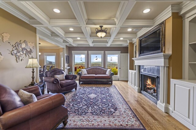 living room featuring a fireplace, light wood-type flooring, coffered ceiling, beamed ceiling, and ornamental molding