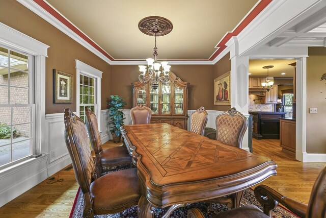 dining room featuring ornamental molding, light wood-type flooring, and a chandelier