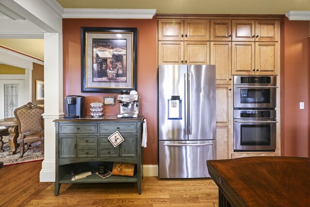 kitchen with light wood-type flooring, appliances with stainless steel finishes, and crown molding