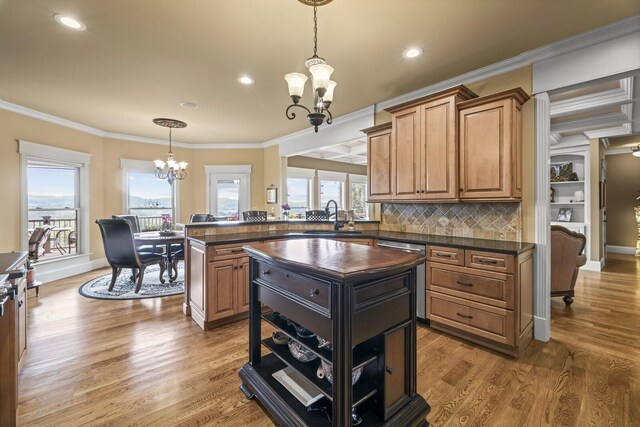 kitchen featuring crown molding, a notable chandelier, sink, wood-type flooring, and a kitchen island