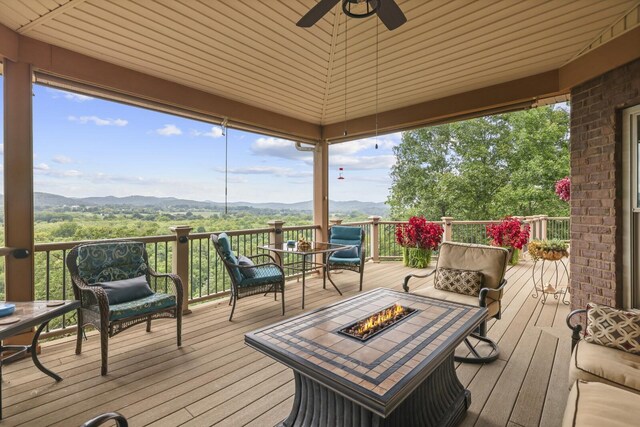 deck featuring a fire pit, a mountain view, and ceiling fan