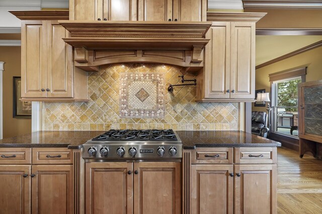 kitchen featuring crown molding, stainless steel stovetop, backsplash, and dark stone counters