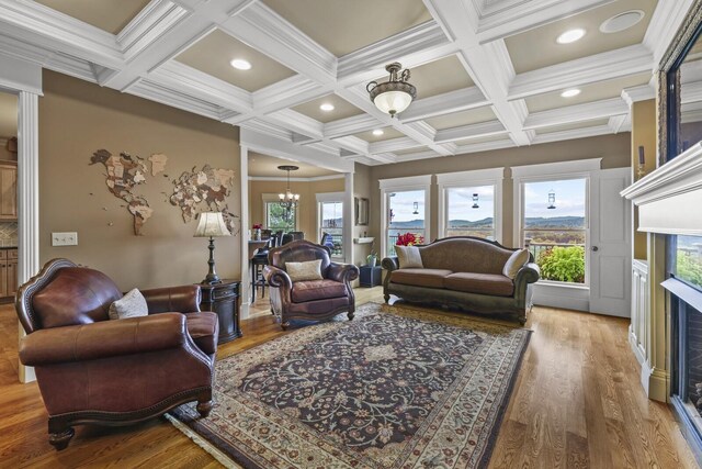 living room featuring hardwood / wood-style floors, a wealth of natural light, coffered ceiling, and crown molding