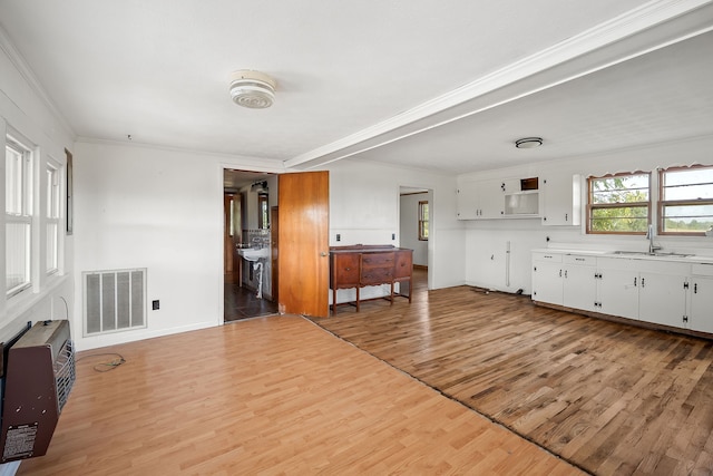 living room with crown molding, light hardwood / wood-style flooring, sink, and a wall unit AC