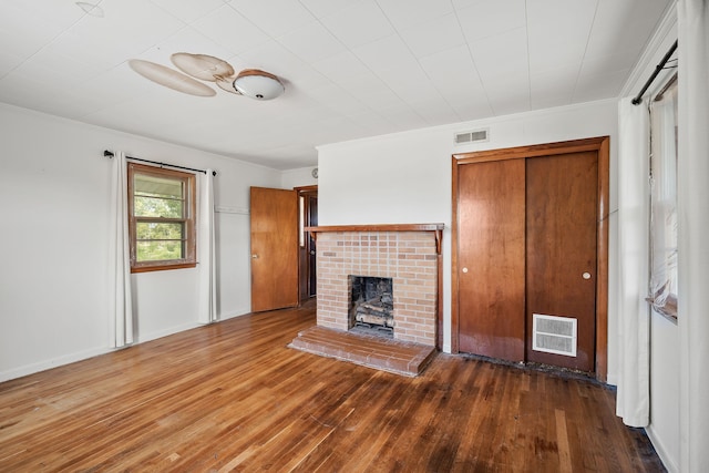 unfurnished living room with hardwood / wood-style floors, ceiling fan, crown molding, and a brick fireplace