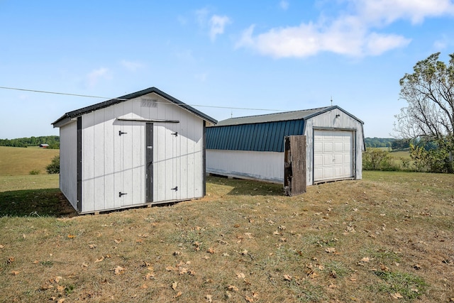 view of outbuilding with a garage, a lawn, and a rural view