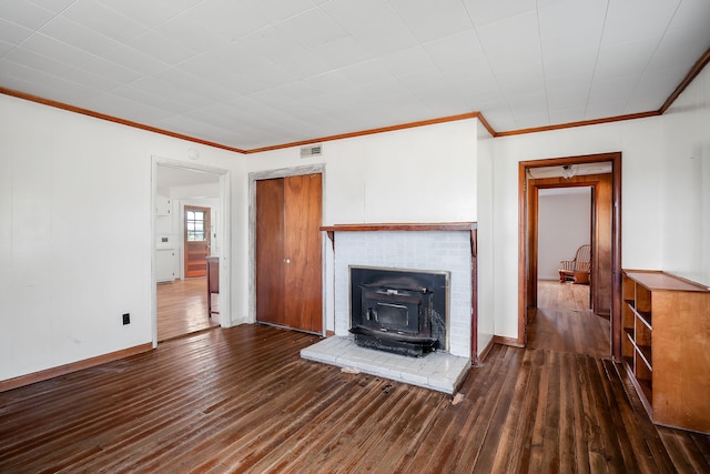 unfurnished living room with a wood stove, dark wood-type flooring, ornamental molding, and a fireplace