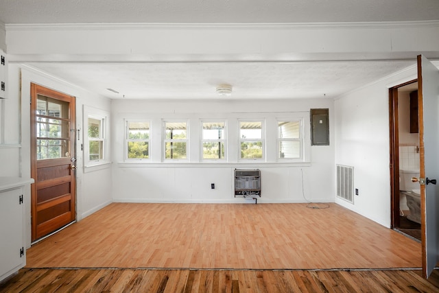 unfurnished living room with electric panel, crown molding, wood-type flooring, and heating unit