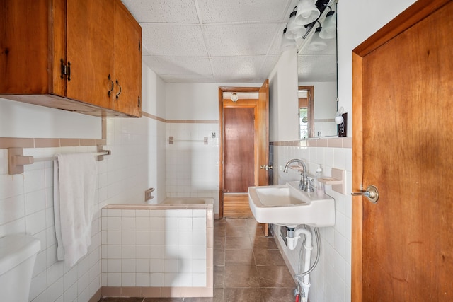 bathroom with tile walls, toilet, tile patterned floors, decorative backsplash, and a drop ceiling