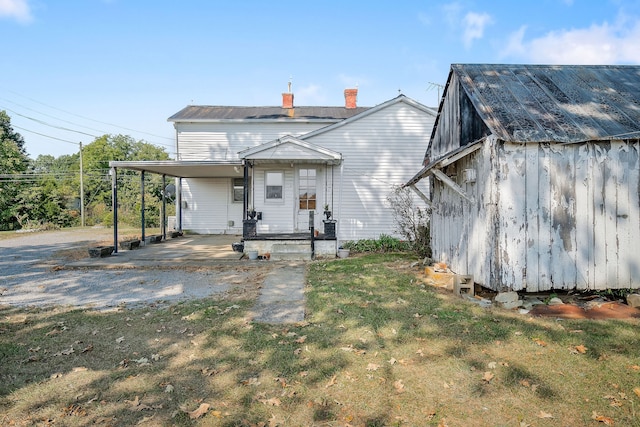 rear view of property featuring a yard, a storage unit, and a carport