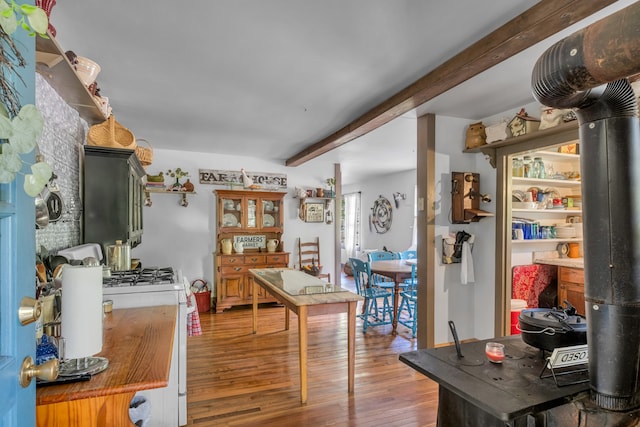 kitchen featuring a wood stove, dark wood-type flooring, white gas range, and beamed ceiling