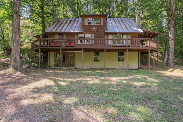 rear view of property featuring a wooden deck and a lawn