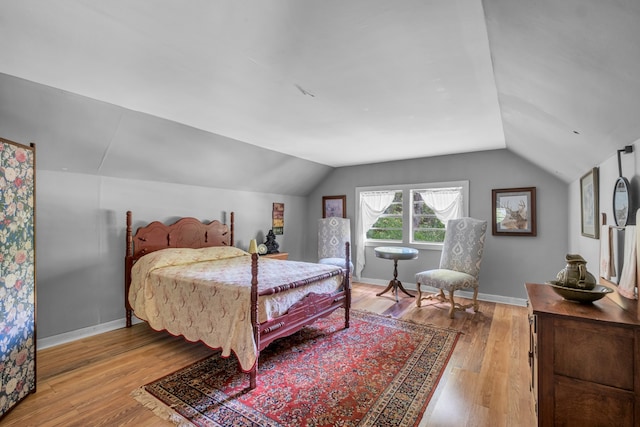 bedroom with light wood-type flooring and vaulted ceiling