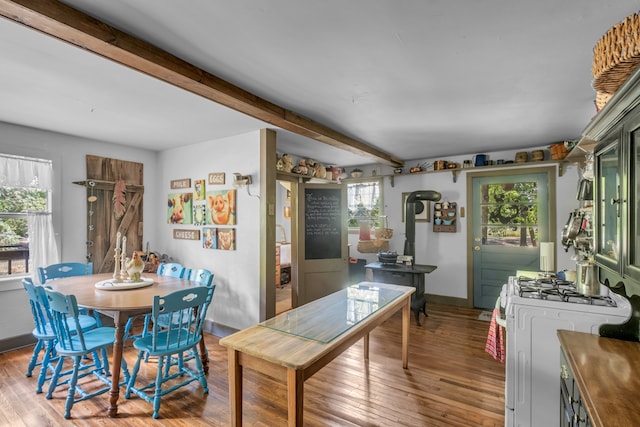 interior space with white range with gas stovetop, dark hardwood / wood-style floors, green cabinetry, and beamed ceiling