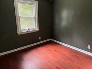 unfurnished room with plenty of natural light and dark wood-type flooring