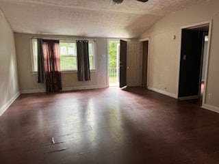 unfurnished room featuring ceiling fan, hardwood / wood-style flooring, a textured ceiling, and vaulted ceiling