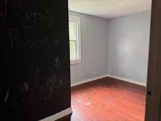 empty room featuring a textured ceiling and hardwood / wood-style floors