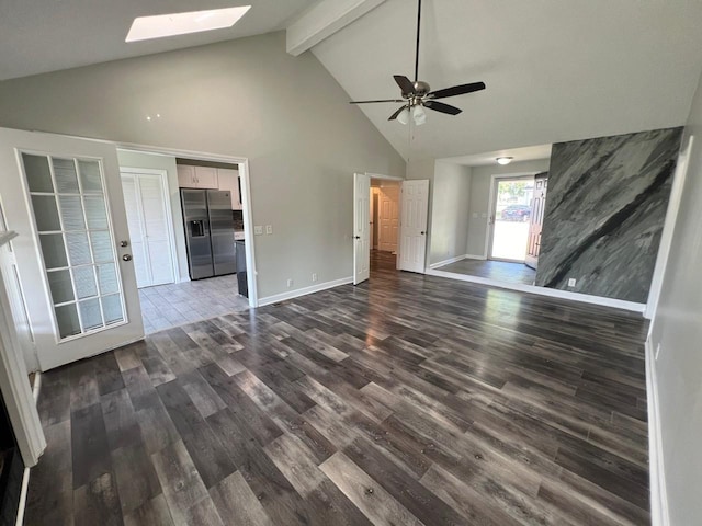 unfurnished living room with a skylight, baseboards, dark wood-style flooring, beamed ceiling, and high vaulted ceiling