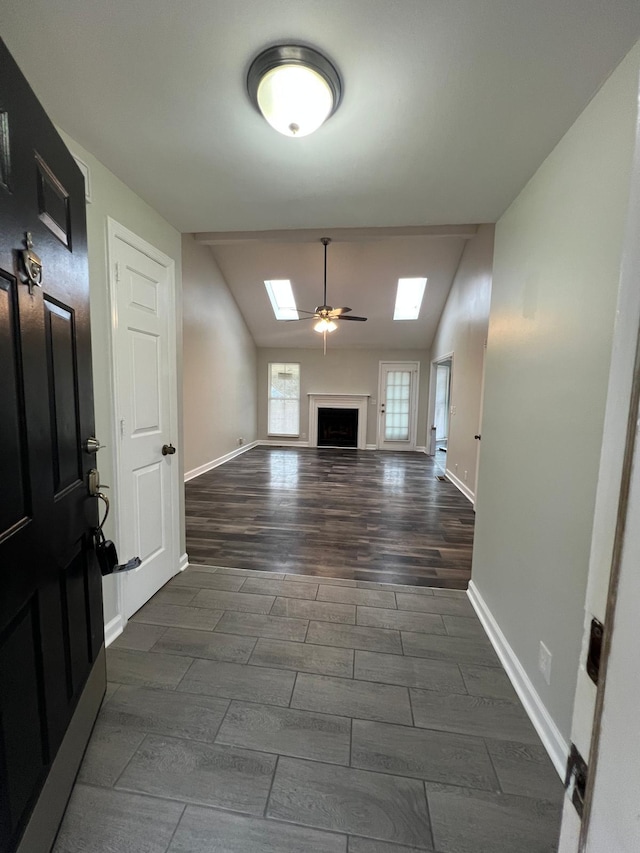 unfurnished living room featuring lofted ceiling with skylight, wood finish floors, a fireplace, and baseboards