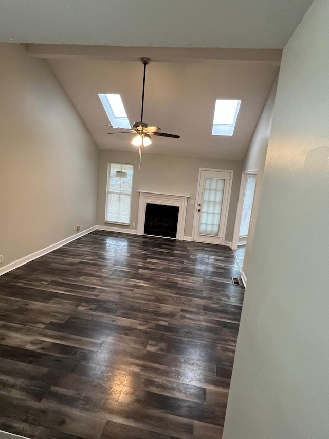 unfurnished living room featuring vaulted ceiling with skylight, baseboards, dark wood finished floors, visible vents, and a fireplace