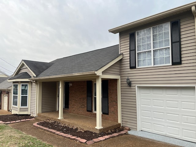 view of front of home with roof with shingles, a porch, and brick siding