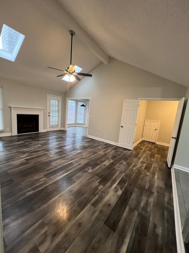 unfurnished living room with ceiling fan, lofted ceiling with skylight, dark wood-style flooring, and baseboards