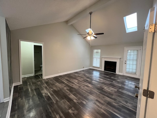 unfurnished living room with a skylight, a fireplace, baseboards, beam ceiling, and dark wood finished floors