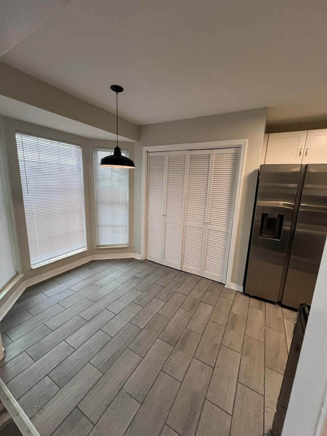 unfurnished dining area featuring baseboards and wood tiled floor