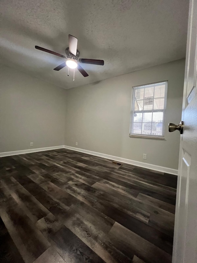 empty room featuring ceiling fan, a textured ceiling, baseboards, and dark wood-type flooring