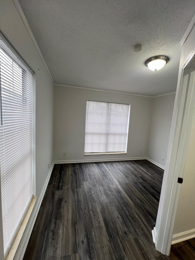 spare room with ornamental molding, dark wood finished floors, a textured ceiling, and baseboards